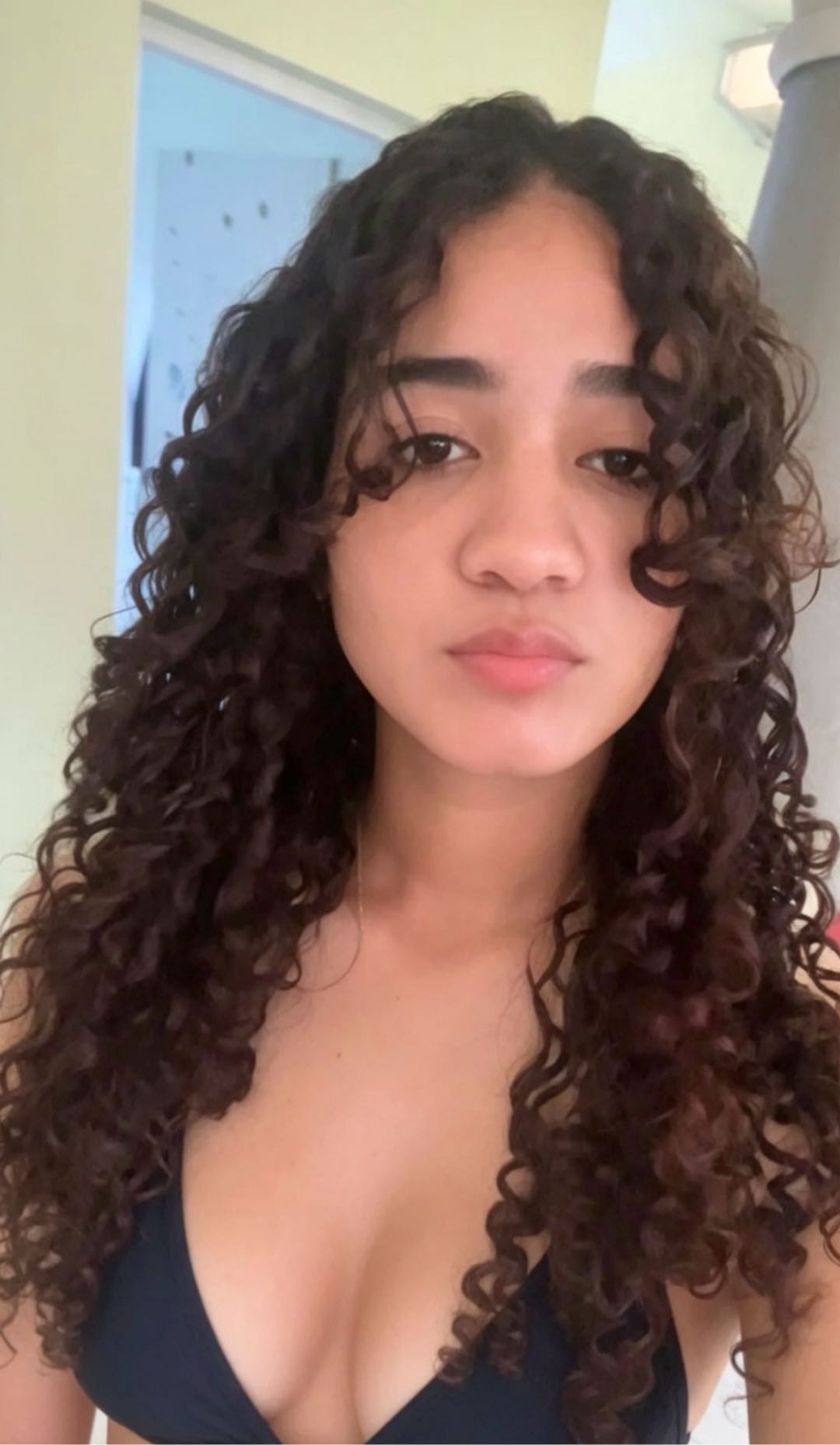 Woman with long dark curly hair, looking at the camera