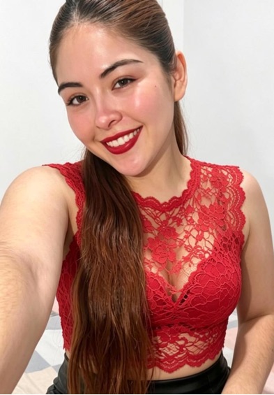 Smiling woman with a long dark ponytail in a red lace top